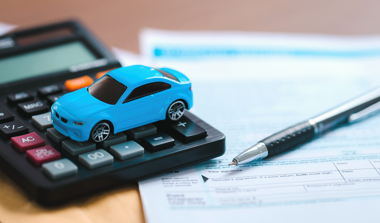 Illustration of a blue toy car sat on a desk calulator next to paen and paper